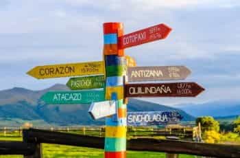 Colorful painted wood signs point the way to different cities on a mountain path in Province Pichincha, Ecuador.
