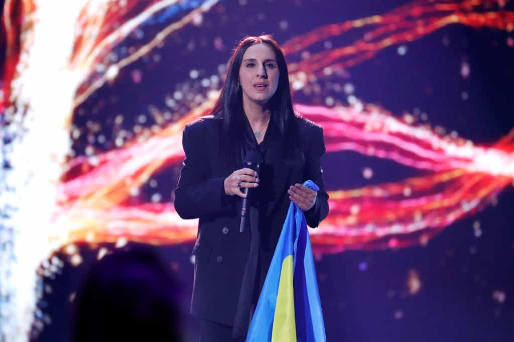 Ukrainian singer Jamala preforms on stage while holding a Ukrainian flag.