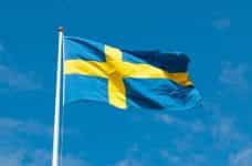 Blue flag with yellow cross flying on white flagpole.