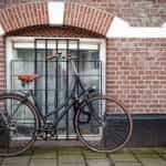 A Dutch city bicycle leaning against a brick wall with white pointing.