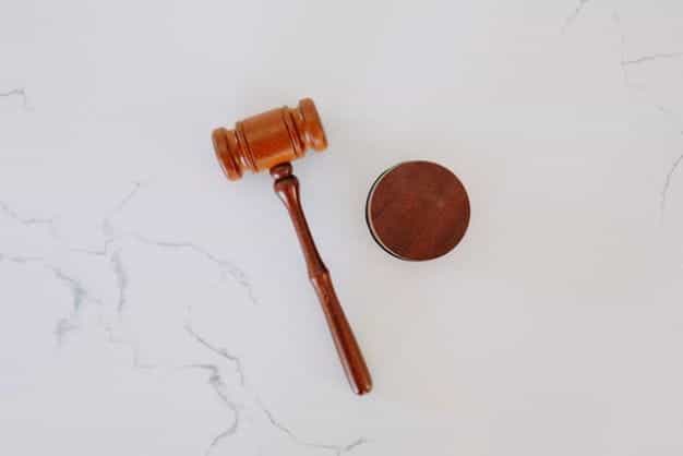 A brown wooden gavel sits atop a gray and white marble tabletop.