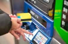A hand inserts a card into an ATM machine.