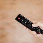 A hand holding a TV remote control.