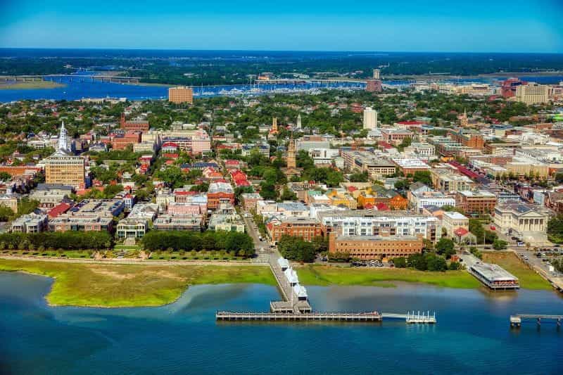 An aerial view of the city of Charleston, South Carolina, banked by large bodies of water on both sides.