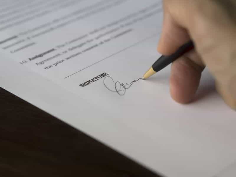 A hand holding a pen signing a contract.