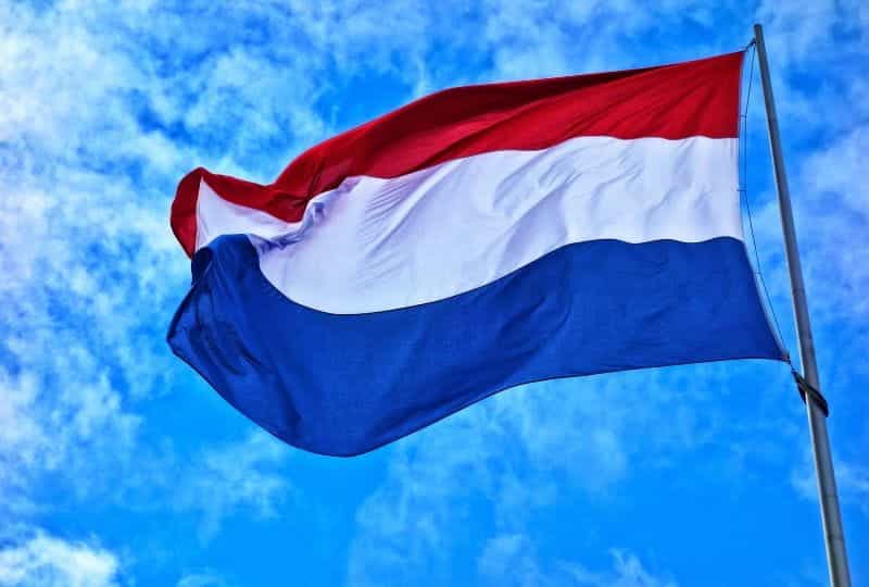Dutch flag flying in wind on a flag pole.