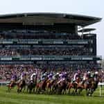 Huge crowds pack an Aintree grandstand as the runners gallop by.