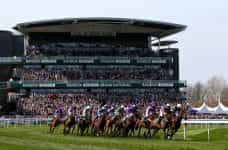 Huge crowds pack an Aintree grandstand as the runners gallop by.