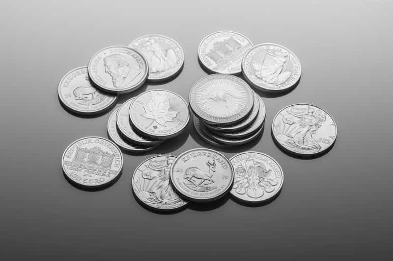 A smattering of silver coins sits on a white surface.