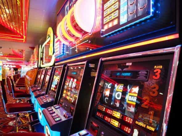 Slot machines in a gaming hall are lit up with red lights.