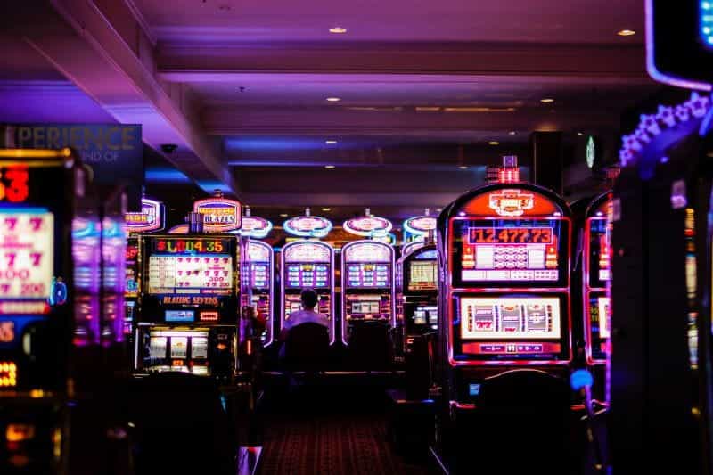 Many rows of slot machines glow in a gaming hall.