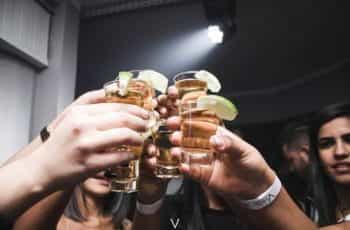 A group of people holding up shot glasses of alcohol in a bar.