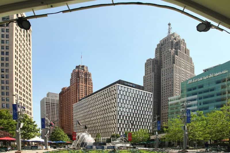 Downtown Detroit, Michigan, featuring several large, imposing buildings with a small park with fountains in front of them.