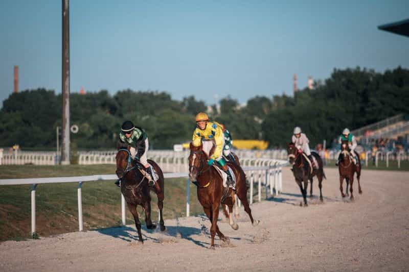 Jockeys racing horses around a track.