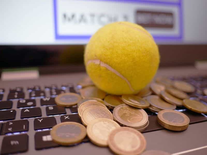A computer with a tennis ball and a selection of euro coins on the keyboard.