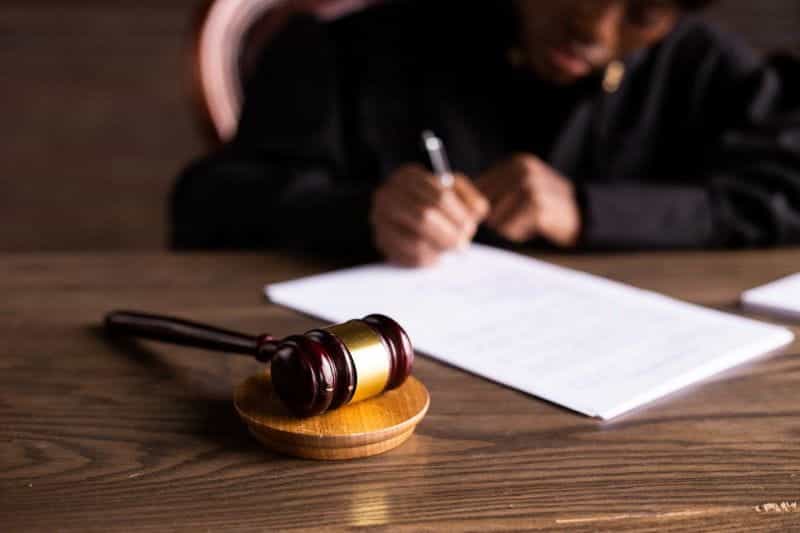 A judge signing a legal document next to a gavel.
