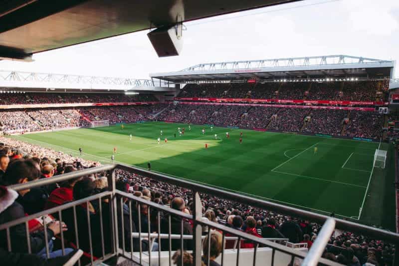 A crowd of football fans watch a match in a large stadium.