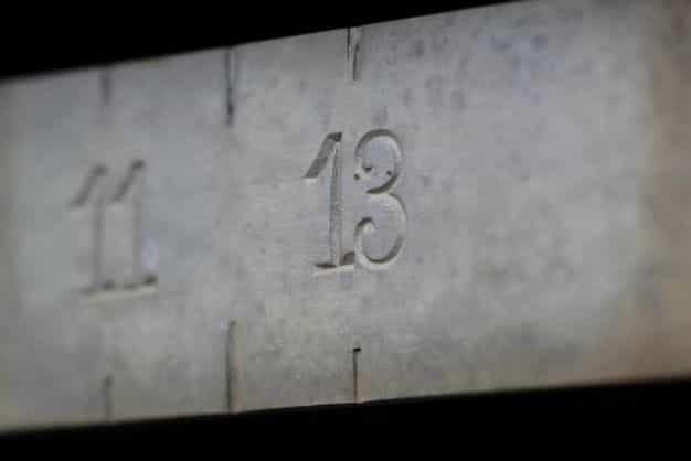 The number 13 is engraved in a concrete, while other numbers around it are blurred.
