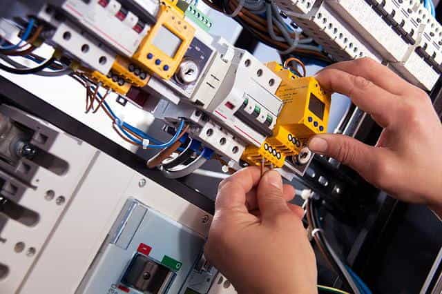 An electrician installing electrical wiring in a cable or grid box.
