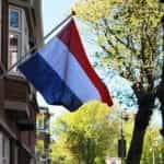 A dutch flag hangs off a building during the daytime.