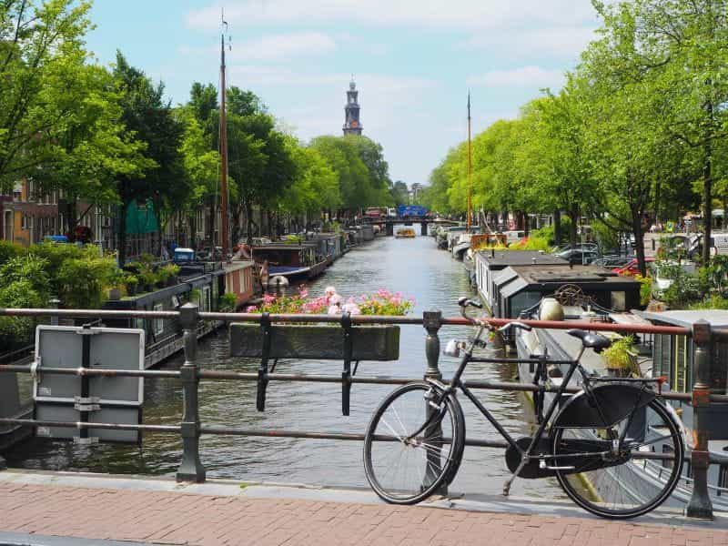 Black bicycle parked beside river during daytime photo in Amsterdam.