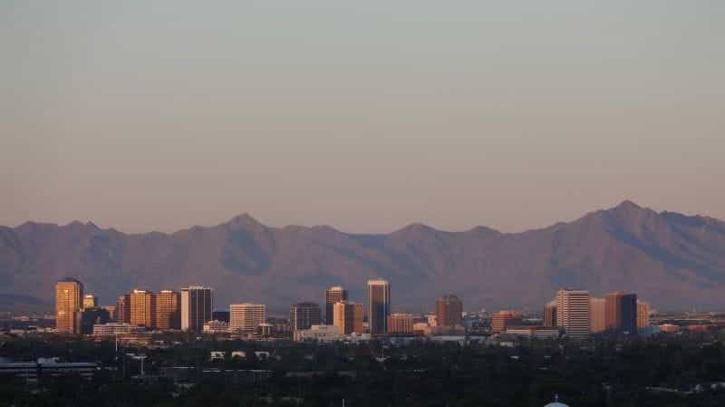 The skyline of the city of Phoenix, Arizona from a far distance, with a mountain range looming behind it.