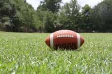 A classic American football sitting on the grass on a football field.