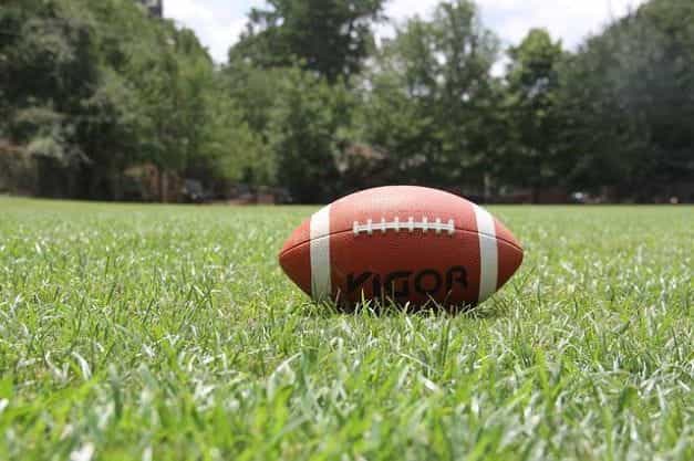 A classic American football sitting on the grass on a football field.