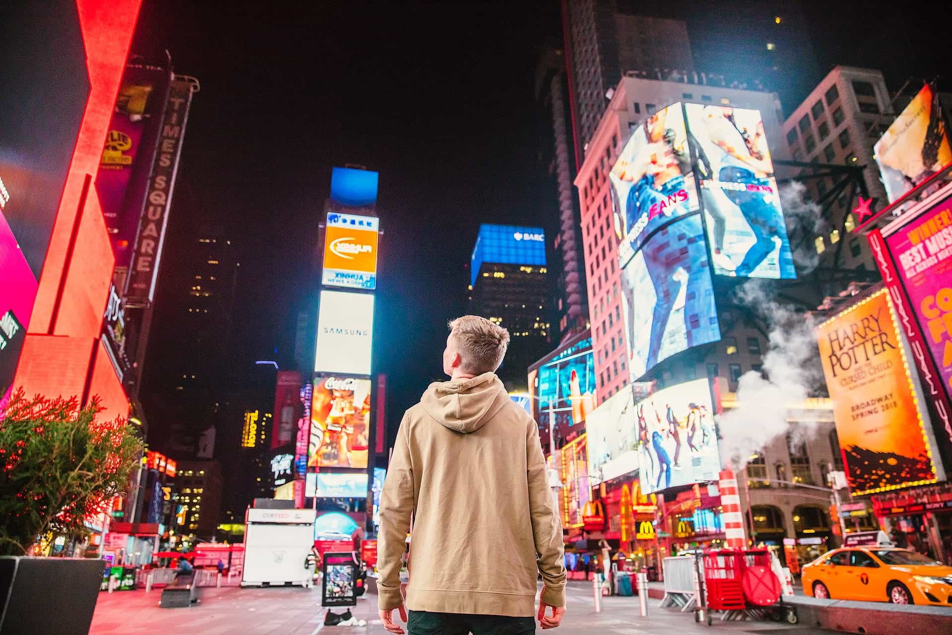 Seorang pria berdiri melihat papan reklame di Times Square, NYC.