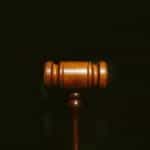 A judge’s gavel stands against a black background.