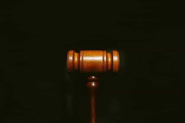 A judge’s gavel stands against a black background.