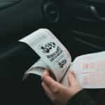 A person holding lottery slips in their left hand.