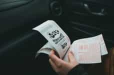 A person holding lottery slips in their left hand.