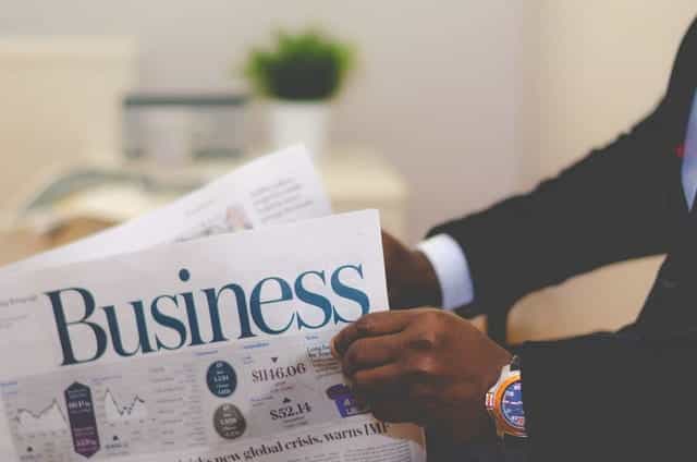 Seorang pengusaha membaca halaman bisnis sebuah surat kabar.