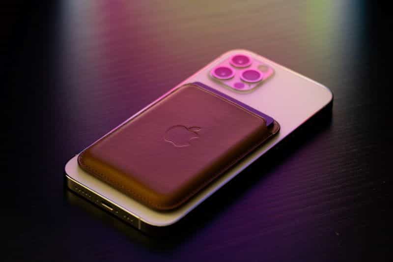 Sebuah iPhone berbaring dengan wajah pertama di atas meja dengan dompet magnet yang menempel di bagian belakang.