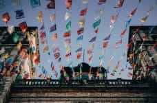 Low angle of colorful flags hanging across a temple in Mexico.