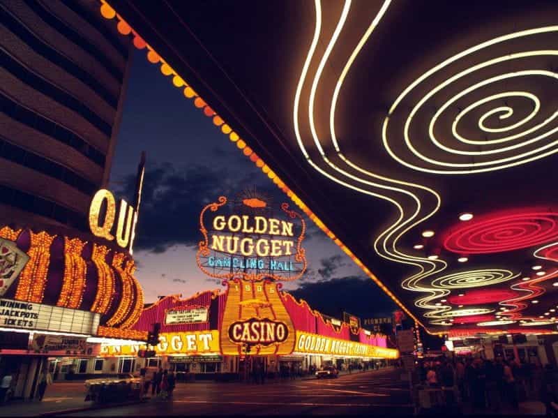 The strip in downtown Las Vegas, with several neon-lit casino businesses on the street.