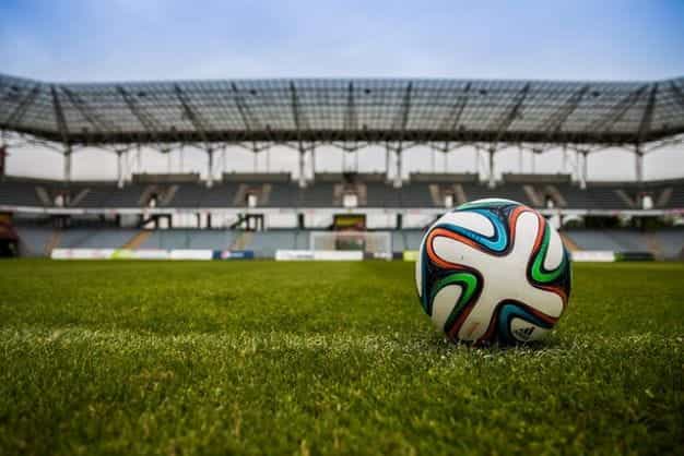 A football on a grass pitch in a stadium.