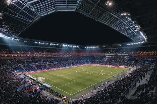 Sebuah stadion sepak bola penuh di malam hari di Lyonnais.