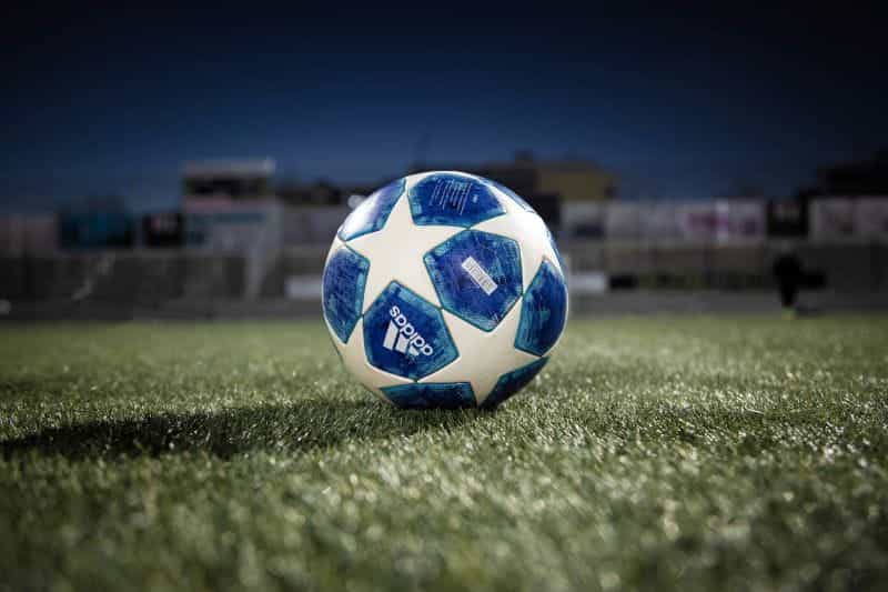 A white and blue soccer ball on a green grass field at night.