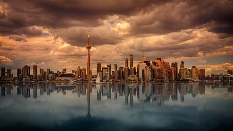 The skyline of Toronto, Ontario in Canada during sunset, with a large body of water extending out in front of it.