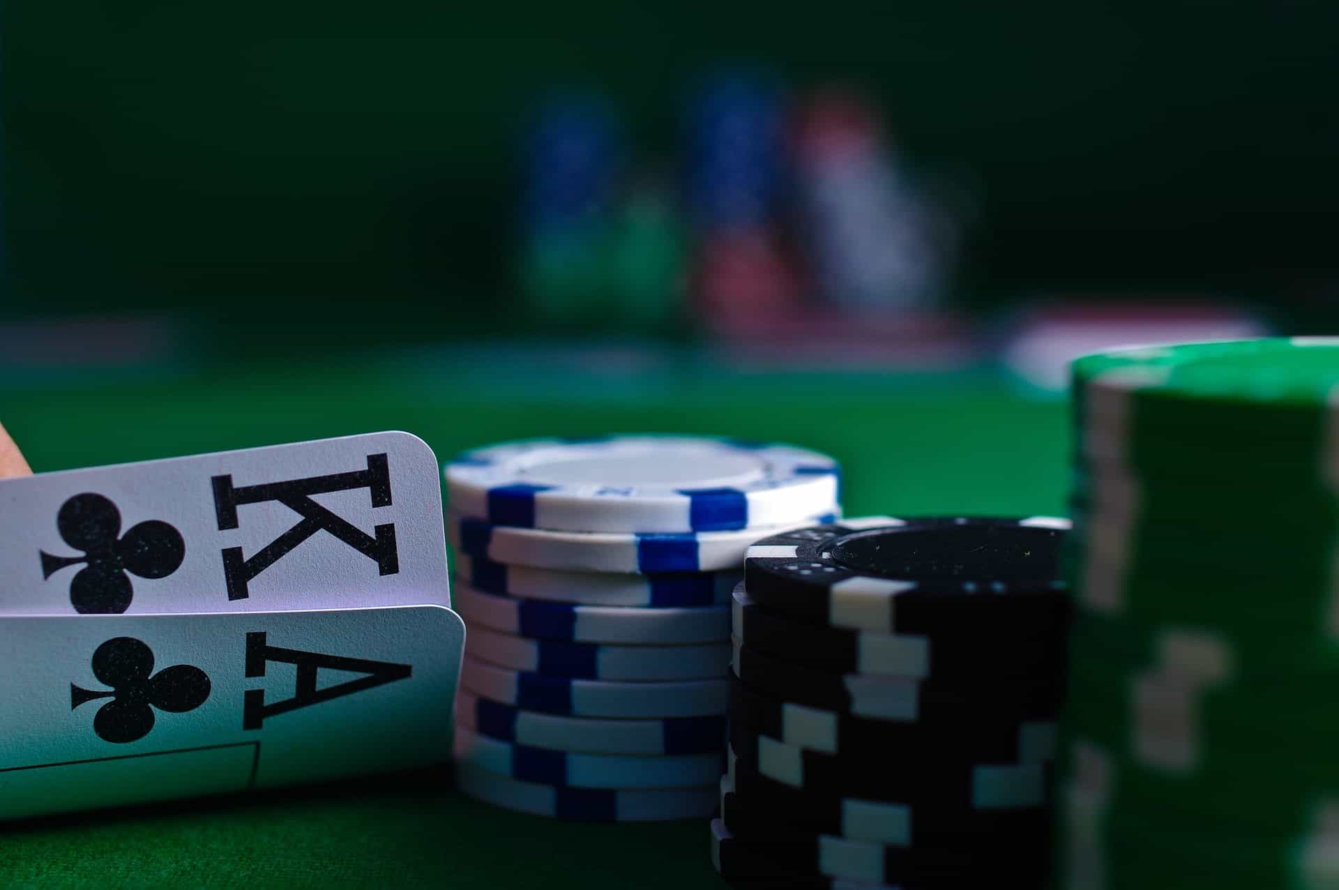A close-up of poker chips and two playing cards on a green felt playing table.