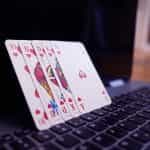 Several playing cards standing in a row and leaning against a laptop computer screen.
