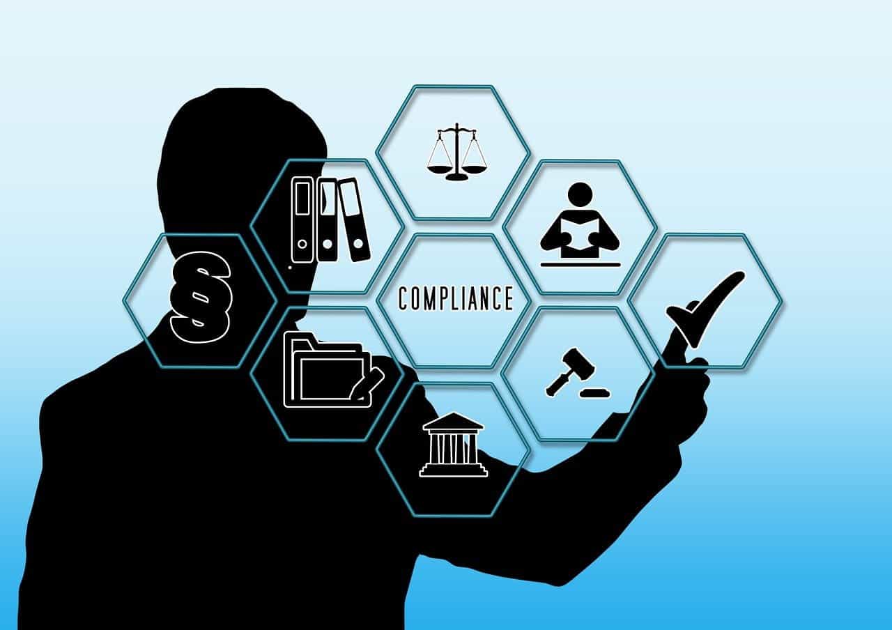 A silhouette of a man pointing to various symbols floating in front of him centered around the theme of compliance, displaying images related to the law and regulations.