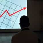 Man observing a projection of a financial graph.
