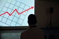 Man observing a projection of a financial graph.