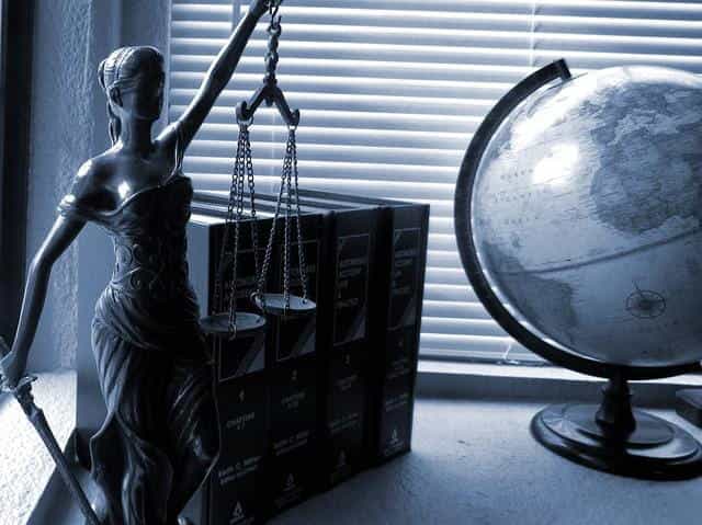 Negara bagian Lady Justice memegang timbangan keadilan berdiri di samping buku-buku hukum dan bola dunia.