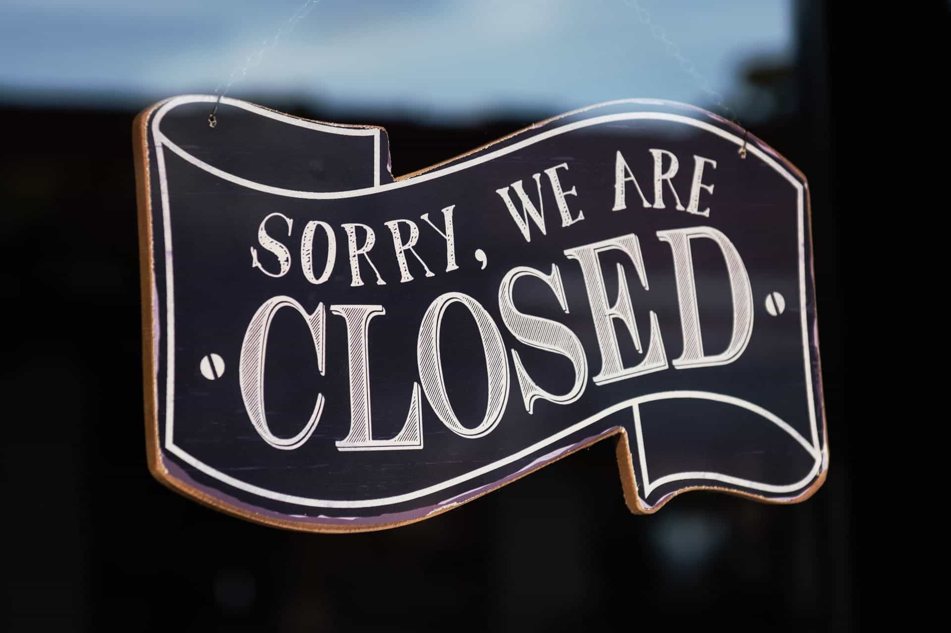 A black and white sign reads "SORRY, WE’RE CLOSED" on a window.