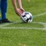 A footballer placing the ball next to a corner flag.