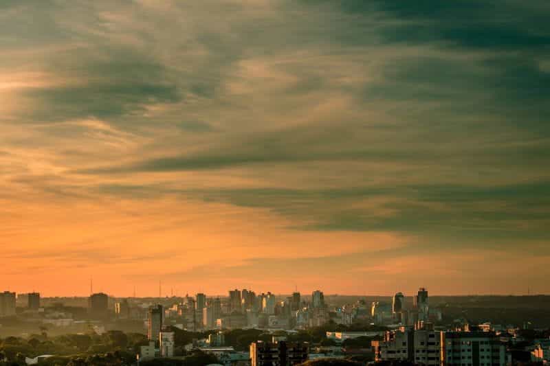 Cakrawala kota Paraguay di bawah langit oranye yang mendung.